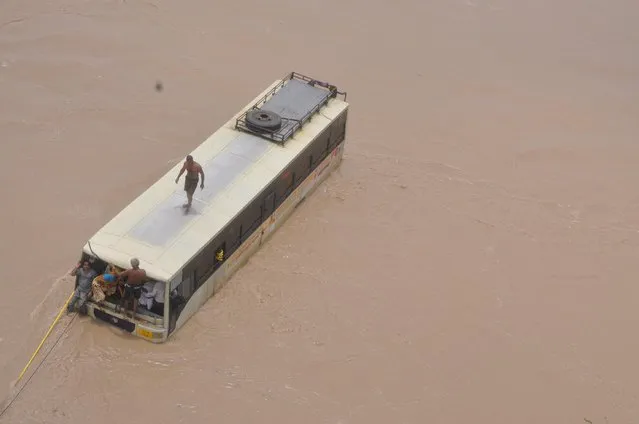 Stranded passengers of a bus wait to be rescued from the flood-affected area of Patan district in Gujarat, India, July 29, 2015. At least 26 people have been killed in the flood like situation caused by torrential monsoon rains in some parts of the western Indian state of Gujarat, local media reported on Thursday. (Photo by Reuters/India's Ministry of Defence)