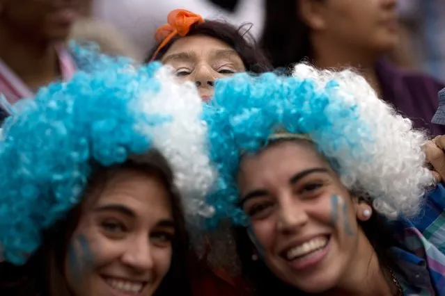 A Netherlands soccer tries to pose for a photo as she is photobombed by two Argentine fans, while they wait for the live telecast of the World Cup semifinal match between Argentina and the Netherlands, at FIFA Fan Fest in Sao Paulo, Brazil, Wednesday, July 9, 2014. (pHOTO BY Rodrigo Abd/AP Photo)