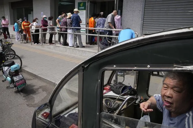 Elderly residents line up to collect their pension as banking services reopen after pandemic measure lockdown are lifted, Tuesday, May 31, 2022, in Beijing. (Photo by Ng Han Guan/AP Photo)