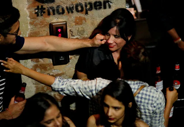 A man grabs the cheek of bouncer Mehrunnisha Shokat Ali at the dance floor of club Social in New Delhi, India, June 23, 2017. Mehrunnisha has been a bouncer for nearly a decade, and for the last three years, has done 10-hour night shifts at Social, which functions as a restaurant and co-working space seating 220 people by day, but morphs into a packed club at night. (Photo by Adnan Abidi/Reuters)