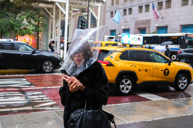 A woman shelters herself from the rain with a plastic bag as she walks along Fifth Avenue in New York, September 28, 2024. (Photo by Charly Triballeau/AFP Photo)