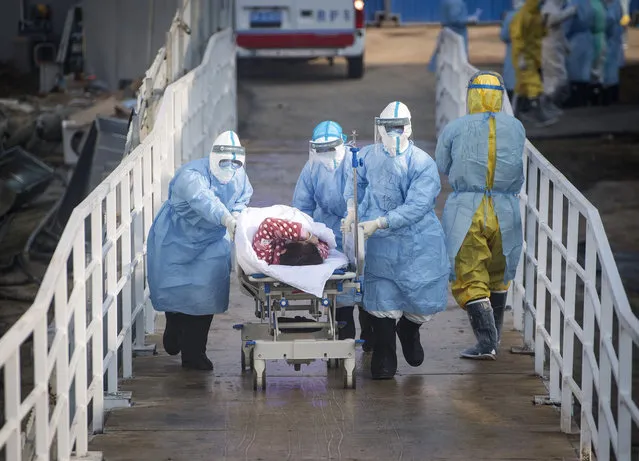 In this photo released by China's Xinhua News Agency, medical workers in protective suits help transfer the first group of patients into the newly-completed Huoshenshan temporary field hospital in Wuhan in central China's Hubei province on February 4, 2020. China said Tuesday the number of infections from a new virus surpassed 20,000 as medical workers and patients arrived at a new hospital and President Xi Jinping said “we have launched a people's war of prevention of the epidemic”. (Photo by Xiao Yijiu/Xinhua via AP Photo)