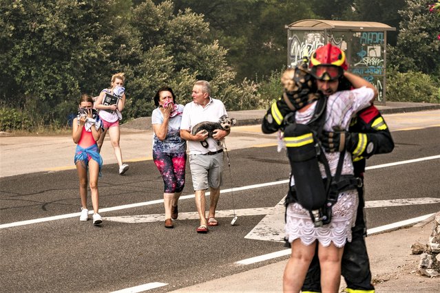 Residents and tourists run from the wildfire in Grebastica, Croatia, Thursday, July 13, 2023. Evacuation orders were issued in several areas as a wildfire swept through coastal areas of the country. (Photo by (Mate Gojanovic/SibenikIN via AP Photo)