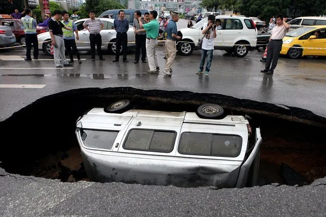 A van is trapped in a hole after a cave-in happened on Fuxing road in Guilin, China, due to long-term rainfall, June 8, 2012