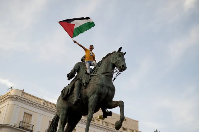 A Pro-Palestinian demonstrator waves a Palestinian flag on top of Carlos III statue in Puerta del Sol Square during a demonstration on July 17, 2014 in Madrid, Spain. (Photo by Pablo Blazquez Dominguez/Getty Images)