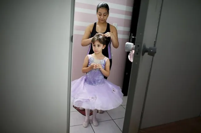 A young girl has her hair styled by a friend before taking ballet lessons at the New Dreams dance studio in the Luz neighborhood known to locals as Cracolandia (Crackland) in Sao Paulo, Brazil, Brazil, August 14, 2015. (Photo by Nacho Doce/Reuters)