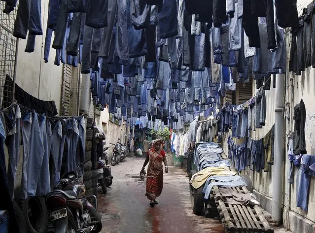 A woman walks through an alley as used pairs of jeans are hung to dry before they are sold in a second-hand clothes market in Kolkata, India, in this June 29, 2015 file photo. (Photo by Rupak De Chowdhuri/Reuters)