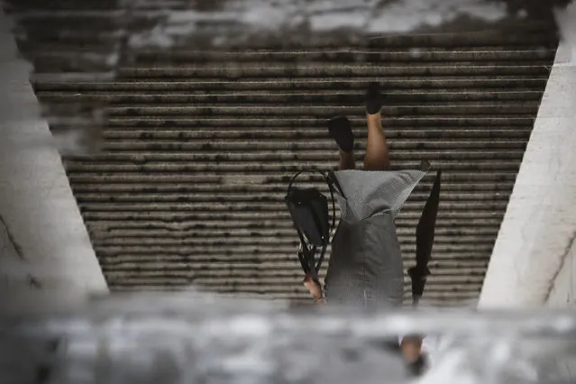 A woman carries a handbag and an umbrella are reflected in a puddle of water as she walks out of an underpass tunnel near the Central Business District after a morning downpour in Beijing, Tuesday, July 18, 2017. Although China's capital is in a semi-dry climate, it receives much of its annual precipitation during the summer months. (Photo by Andy Wong/AP Photo)