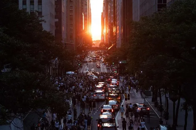The sun sets over Manhattan on 42nd street during “Manhattanhenge” in New York, July 11, 2022. The Manhattanhenge is an event in which the sunset or sunrise is aligned on the east-west grid of main streets in Manhattan, New York. (Photo by Yuki Iwamura/AFP Photo)
