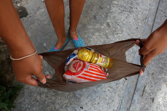 A resident shows a bag of food, which includes a bottle of cooking oil, a chicken and other staples,  which she bought under a new government system in providing basic food at low cost, in Caracas, Venezuela July 9, 2016. (Photo by Carlos Jasso/Reuters)