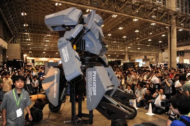 Japanese electronics company Suidobashi Heavy Industry unveils its latest robot “Kuratas” (C) as a crowd of people take photographs at the Wonder Festival in Chiba, suburban Tokyo on July 29, 2012. The Kuratas robot, which will go on sale with a price tag of one million USD, measures four meters in height, weighs four tons and has four wheeled legs that can either be controlled remotely through the 3G network or by a human seated within the cockpit.