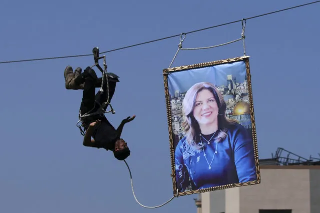 A Hamas security officer pulls a picture of slain Palestinian-American journalist Shireen Abu Akleh during a presentation at a graduation ceremony for Al-Rebat College's Police Academy, in Khan Younis, southern Gaza Strip, Thursday, June 30, 2022. (Photo by Adel Hana/AP Photo)