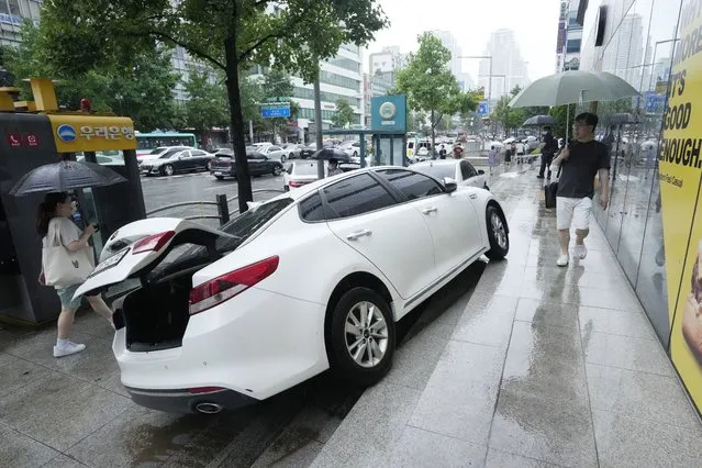 A vehicle is damaged on the sidewalk after floating in heavy rainfall in Seoul, South Korea, Tuesday, August 9, 2022. (Photo by Ahn Young-joon/AP Photo)