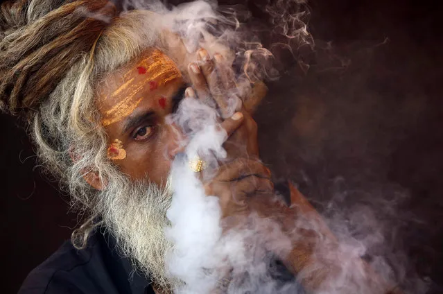 A Naga sadhu, or naked Hindu holy man, smokes hashish inside his tent during Kumbh Mela, or Pitcher festival, at Trimbakeshwar, India, Friday, August 28, 2015. Hindus believe taking a dip in the waters of a holy river during the festival will cleanse them of their sins. The festival is held four times every 12 years. (Photo by Rajanish Kakade/AP Photo)