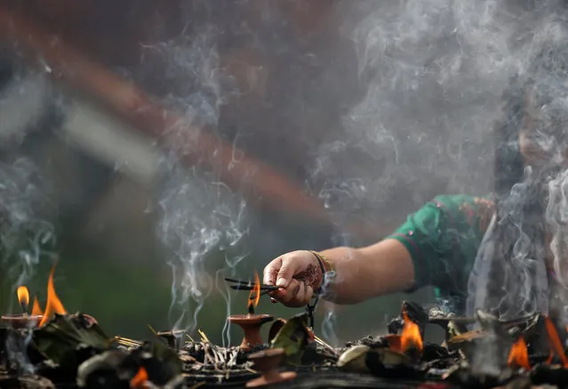 A devotee light incenses while offering prayers at Pashupatinath temple to mark the Shrawan Sombar festival in Kathmandu, Nepal, July 18, 2016. (Photo by Navesh Chitrakar/Reuters)