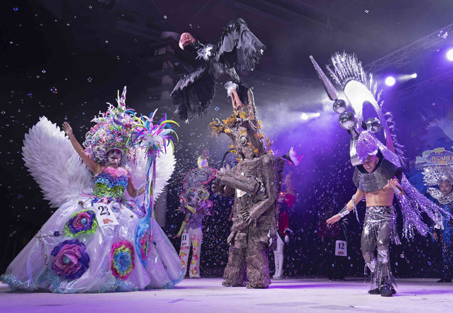 In this photo provided by the Florida Keys News Bureau, the top three finishers at the Fantasy Fest Headdress Ball prance on the stage at the conclusion of the event Thursday, October 26, 2023, in Key West, Fla. From left to right are Erica Rachel, who won with her “The Unicorn Realm” entry; Alex Okinczyc, who got third place with “Tobanga the Walking Tree” and Guy Hermelin, who came in second with “The Derby Dazzler”. (Photo by Rob O'Neal/Florida Keys News Bureau via AP Photo)