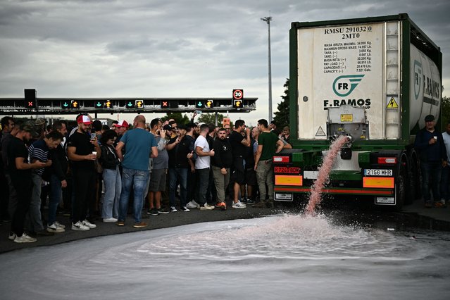 Winegrowers unload wine from a lorry during a road blocking demonstration to protest against imports of Spanish wine, on the motorway at the toll booth of Le Boulou, close to the Spanish border, southern France, on October 19, 2023. Winegrowers in southern France have called for demonstrations to demand economic efforts to help the regional wine industry, which has gone through a trying vintage amid difficult climatic conditions. (Photo by Lionel Bonaventure/AFP Photo)