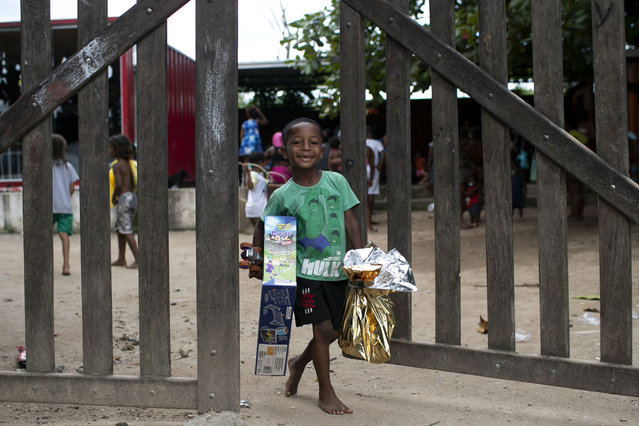 A child carries Christmas donations from the SOMOS social movement, a non-governmental organization working to fight hunger, in the Jardim Gramacho favela, in Duque de Caxias, Rio de Janeiro state, Sunday, December 15, 2024. (Photo by Bruna Prado/AP Photo)