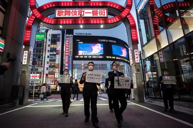 Staff members of the Tokyo metropolitan government wearing face masks hold signs as they call people to stay home in the Kabukicho entertainment area on April 11, 2020 in Tokyo, Japan. Tokyo Governor Yuriko Koike has requested that businesses including schools, athletic facilities, bars and restaurants to temporarily close or operate under reduced hours. The action follows a state of emergency that covers 7 of Japans 47 prefectures as the Covid-19 coronavirus outbreak continues to spread throughout the country. (Photo by Tomohiro Ohsumi/Getty Images)