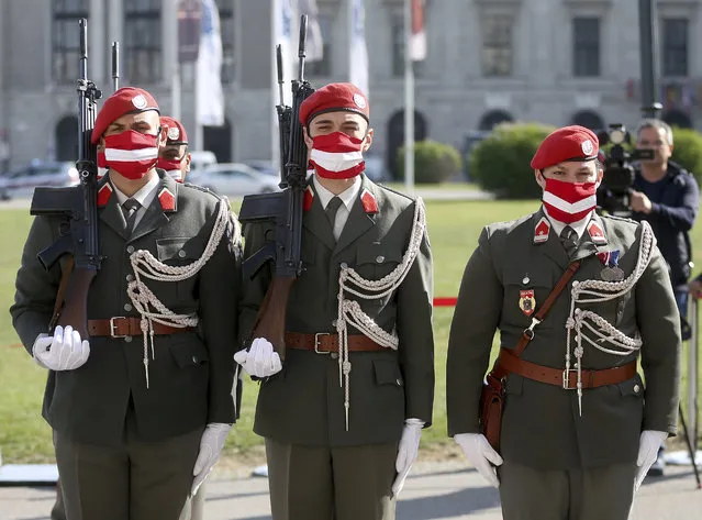 Austrian soldiers wear protective masks showing the Austrian national flag during a military ceremony on the occasion of the 75th anniversary of the re-establishment of the Republic of Austria in Vienna, Austria, Monday, April 27, 2020. The Austrian government has moved to restrict freedom of movement for people, in an effort to slow the onset of the COVID-19 coronavirus. (Photo by Ronald Zak/AP Photo)