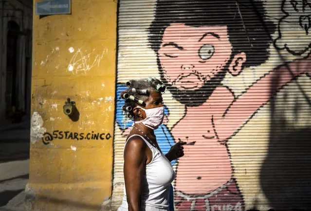 A woman wearing a mask as a precaution against the spread of the new coronavirus walks down the street in Havana, Cuba, Tuesday, March 31, 2020. Cuban authorities are requiring the use of masks for anyone outside their homes. (Photo by Ramon Espinosa/AP Photo)