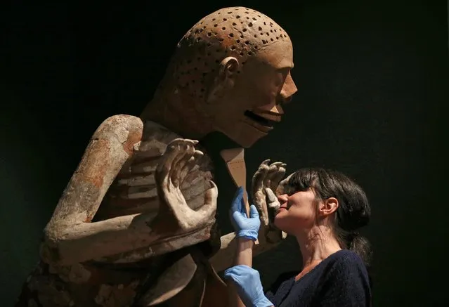 Australian Museum conservator Heather McKay inspects a piece depicting Mictlantecuhtli, God of Death and Lord of the Underworld, from the Aztecs exhibition in Sydney, Thursday, September 11, 2014. More than 200 stone, terra-cotta and other artifacts are on display showcasing the Aztec history and culture in the exhibition that opens Saturday and runs through to Feb. 1, 2015. (Photo by Rick Rycroft/AP Photo)