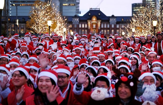 Workers dressed as Santa Claus pose for photos before their parade at Marunouchi business district located near Tokyo Station (rear) in Tokyo on December 22, 2023. (Photo by Kazuhiro Nogi/AFP Photo)