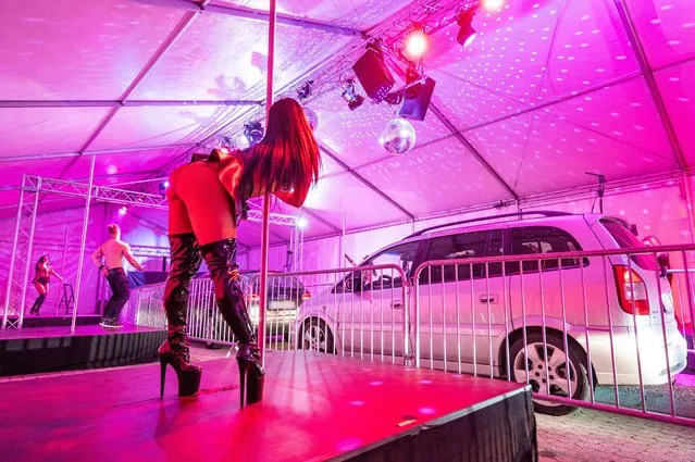 Dancers stand in strip-drive-in on stages in front of cars in Landshut, Bavaria on May 29, 2020. In the Strip-Drive-In the car passengers can admire the strippers at the prescribed minimum distance. The shows take place on Friday and Saturday between 11pm and 3am local time and cost €35. Motorists are allowed into the tent but only for around 15 minutes. (Photo by Armin Weigel/dpa)