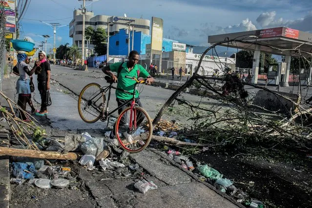 A man carries a bicycle while crossing a barricade in Port-au-Prince, Haiti, Wednesday, October 12, 2022. (Photo by Joseph Odelyn/AP Photo)