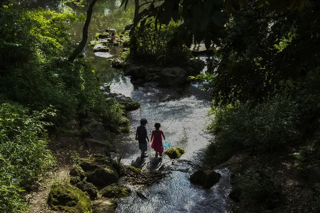 Children play in a stream at the Arisugawa Park, Saturday, May 30, 2020, in Tokyo. Japanese Prime Minister Shinzo Abe has announced the lift of a coronavirus state of emergency from Tokyo and four other remaining areas, ending the restrictions nationwide as businesses begin to reopen. (Photo by Kiichiro Sato/AP Photo)