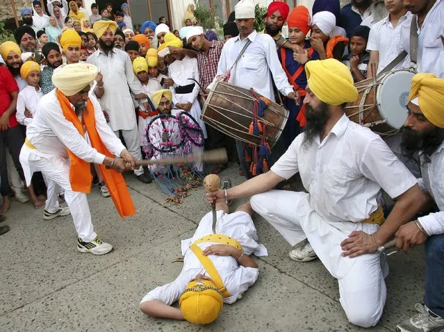 A Sikh performer breaks a coconut with a stick as he performs Gatkha, a traditional form of martial art, during a religious procession in Amritsar, India, September 14, 2015. The procession was carried out to celebrate the 411th anniversary of the installation of the Guru Granth Sahib, the religious book of Sikhs. (Photo by Munish Sharma/Reuters)