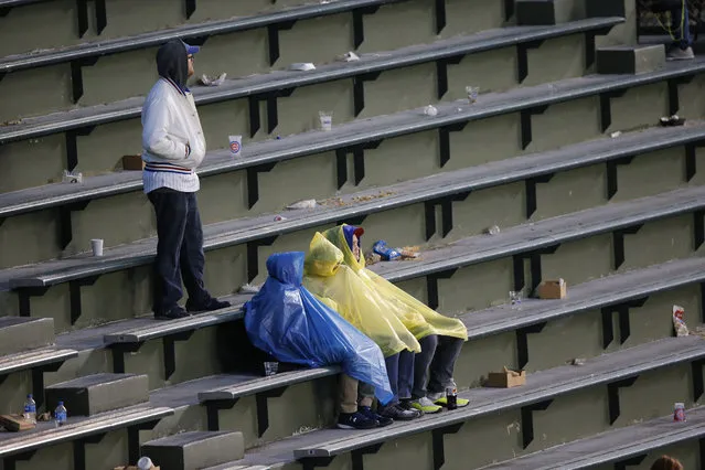 Fans sit on the bleachers during the weather delay before Game 4 of baseball's National League Division Series between the Chicago Cubs and the Washington Nationals, Tuesday, October 10, 2017, in Chicago. The game was postponed until Wednesday due to rain. (Photo by Charles Rex Arbogast/AP Photo)