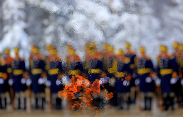 Soldiers of the Romanian Presidential Honor Guard, as seen through the eternal flame that burns for the fallen heroes, pay respect in front of the Unknown Soldier Memorial during a religious ceremony organized to mark the 165th anniversary of the Unification of the Romanian Principalities, in Bucharest, Romania, 24 January 2024. The Day of the Unification of the Romanian Principalities, also known as the “Little Union Day”, is a public holiday of Romania that is celebrated every 24 January in order to commemorate the unification of the Romanian Principalities, performed on 24 January 1859 under the prince Alexandru Ioan Cuza. (Photo by Robert Ghement/EPA/EFE)
