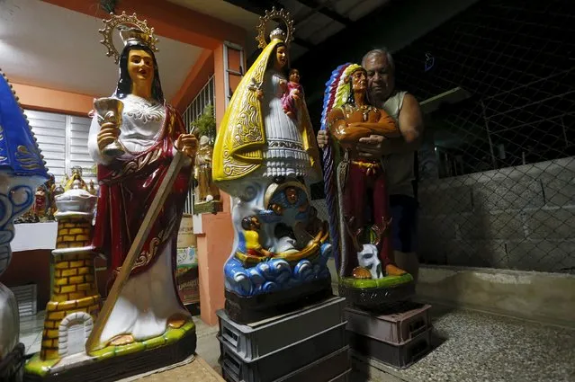 Aramis Amaro arranges a figurine of the Indian, a guardian angel for followers of the Afro-Cuban religion, next to Saint Barbara (L) and the Virgin of Copper, which are for sale, outside his house in Rincon on the outskirts of Havana, September 17, 2015. (Photo by Reuters/Stringer)