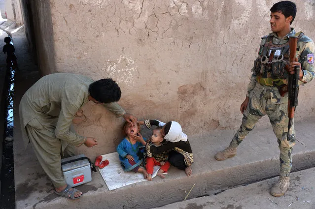 An Afghan health worker administers polio drops to a child during a polio vaccination campaign in the Surkh Rod district of Nangarhar province on August 29, 2016. Afghanistan launched a polio vaccination campaign on August 29, aimed at reaching children in areas previously controlled by Islamic State group militants, officials said. (Photo by Noorullah Shirzada/AFP Photo)