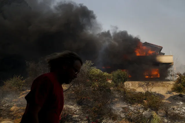 A man walks past a home consumed by a wildfire Tuesday, December 5, 2017, in Ventura, Calif. (Photo by Jae C. Hong/AP Photo)