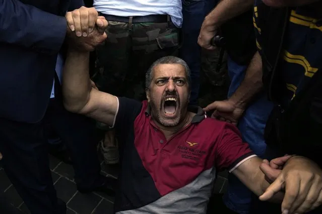 A retired army member lies on the ground and chants slogans as others try to enter to the parliament building while the legislature was in session discussing the 2022 budget in downtown Beirut, Lebanon, Monday, September 26, 2022. (Photo by Bilal Hussein/AP Photo)