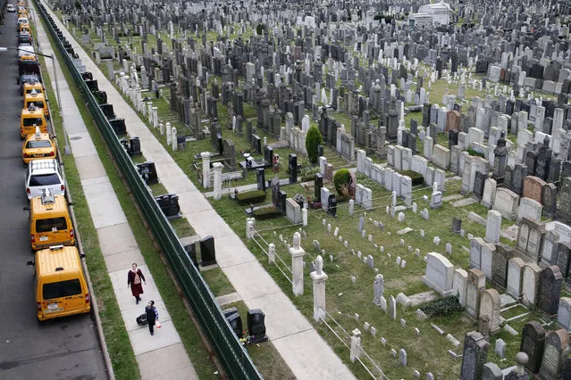 In this Oct. 13, 2014 photo, two people walk past Washington Cemetery in the Brooklyn borough of New York. The predominantly Jewish cemetery dates back to the late 1800's and is almost filled to capacity. (AP Photo/Kathy Willens)
