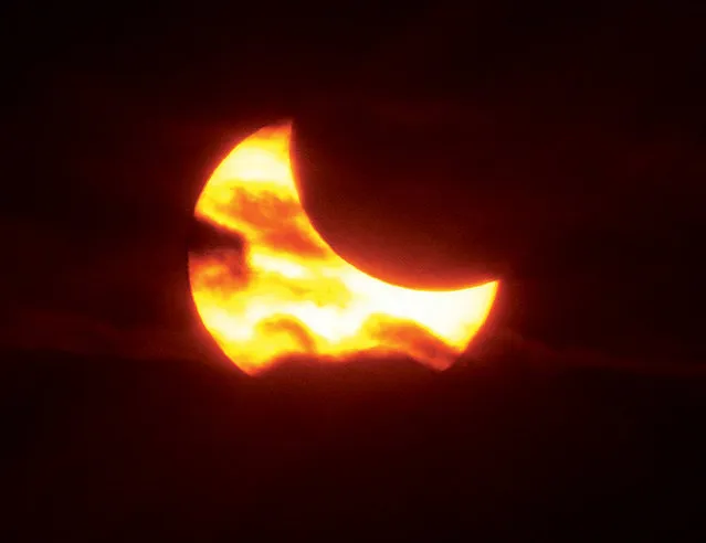 The moon passes between the earth and the sun Thursday, October 23, 2014, near the totality stage of a partial solar eclipse as seen from West Alton, Mo. Heavy clouds blocked the entire eclipse except for about 2 minutes when it found a view through an opening in the clouds. (Photo by John Badman/AP Photo/The Telegraph)