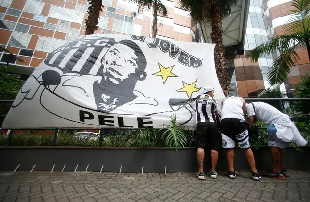 Fans of Santos place a flag with the image of Brazilian football legend Pele during a vigil outside the Albert Einstein Israelite Hospital entrance, where he is hospitalized in Sao Paulo, Brazil, on December 4, 2022. Brazilian football legend Pele said on Saturday that he feels “strong, with a lot of hope” despite medical problems that have kept the 82-year-old sports icon in the hospital with a respiratory infection. (Photo by Miguel Schincariol/AFP Photo)