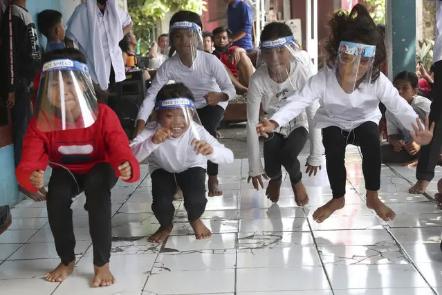 Children wearing masks as a precaution against the coronavirus, take part in a “leap frog” race during a performance held as a part of a celebration of the country's 75th anniversary of independence in Tangerang, Indonesia, Monday, August 17, 2020. (Photo by Tatan Syuflana/AP Photo)