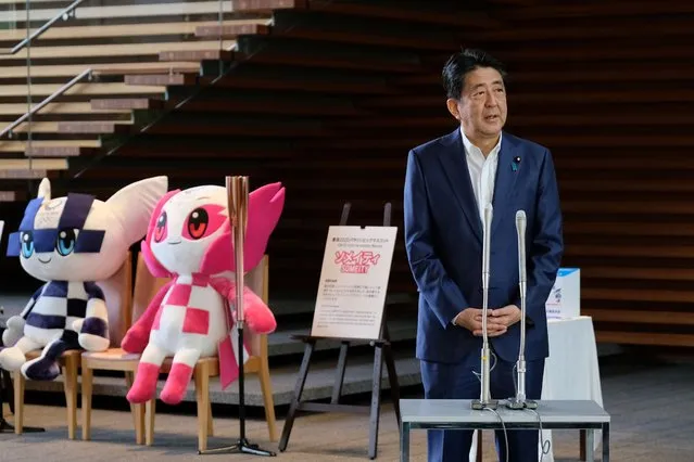 Japan's Prime Minister Shinzo Abe speaks to the media upon his arrival at the entrance of the Prime Minister's office, as Tokyo 2020 Olympic mascot Miraitowa (L), and Paralympic mascot Someity (2nd L) are seen on August 24, 2020. Abe earlier in the day returned to hospital on August 24 for more medical checks, a government spokesman said, a week after a first visit that fuelled growing speculation about his health. (Photo by Kazuhiro Nogi/AFP Photo)