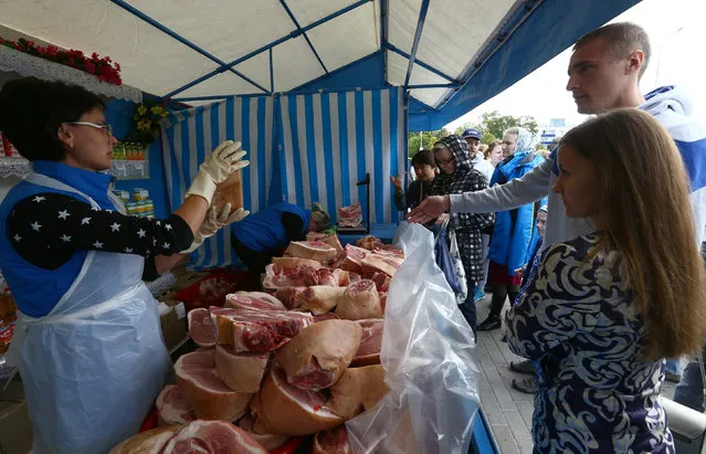 A seller shows pork to customers at a market during the annual autumn agriculture fair in Minsk, Belarus September 18, 2016. (Photo by Vasily Fedosenko/Reuters)