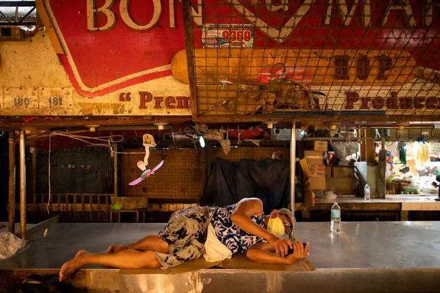 A meat vendor rests on a meat stand at a public market where wearing face masks and face shields is mandatory, amid the coronavirus disease (COVID-19) outbreak in Taytay, Rizal province, Philippines, August 11, 2020. (Photo by Eloisa Lopez/Reuters)