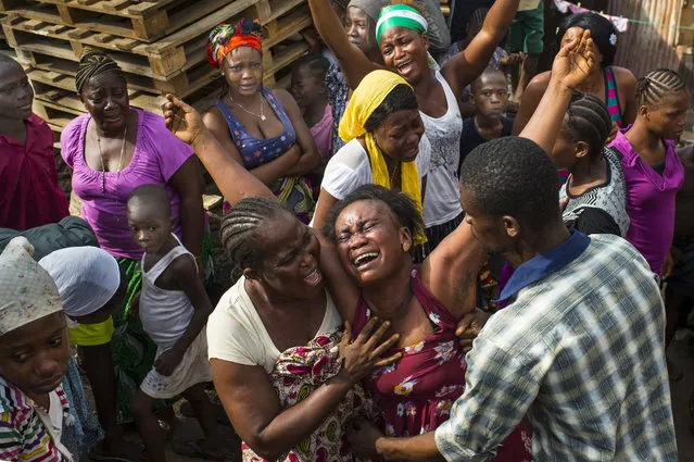 Family members mourn the death of 12-year-old Isata Kallon in Freetown, Sierra Leone, as Ebola cases continue to rise on Sunday, November 23, 2014. Swabs are taken from the deceased to test for Ebola and all burials in Sierra Leone adhere to strict rules to prevent the spread of the disease. (Photo by Nikki Kahn/The Washington Post)