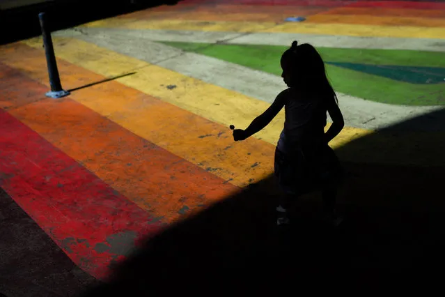 A girl plays as she walks through the Paseo Bandera in Santiago, Chile, Thursday, January 19, 2023. (Photo by Matias Delacroix/AP Photo)