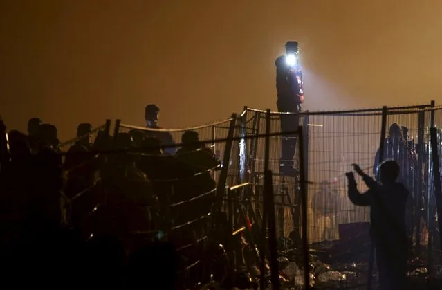 Austrian police guard migrants as they wait to cross the Slovenia-Austria border in Sentilj, Slovenia, October 27, 2015. (Photo by Srdjan Zivulovic/Reuters)