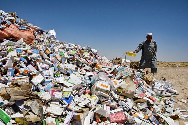 An Afghan official pours a chemical to set aflame a heap of seized expired medicines at a field on the outskirts of Mazar-i-Sharif on June 2, 2025. (Photo by Atif Aryan/AFP Photo)