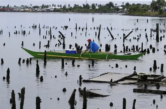 A fisherman paddles his banca amidst ruins of house stilts destroyed by Typhoon Haiyan on a coastal village in Tacloban city in central Philippines November 2, 2015, ahead of the second anniversary of the devastating typhoon that killed more than 6,000 people in central Philippines. (Photo by Erik De Castro/Reuters)