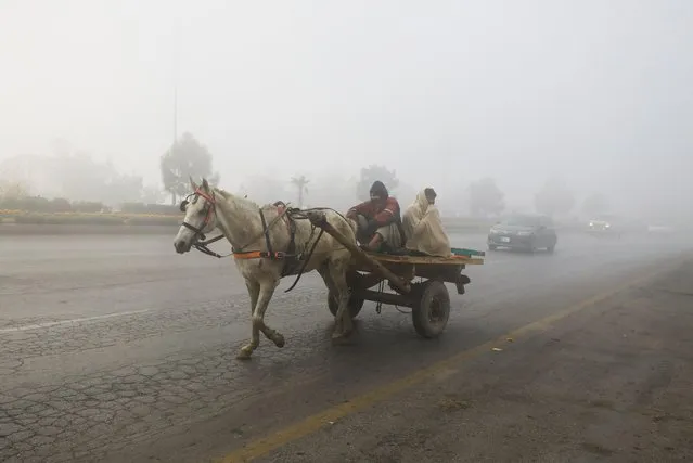 Men ride on a horse cart amid fog during morning hours in Peshawar, Pakistan on December 22, 2022. (Photo by Fayaz Aziz/Reuters)